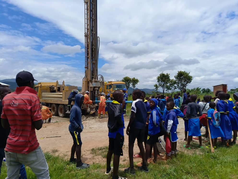 Young villagers gathered around a drilling rig boring a fresh water well hole in their village for the first time ever. 